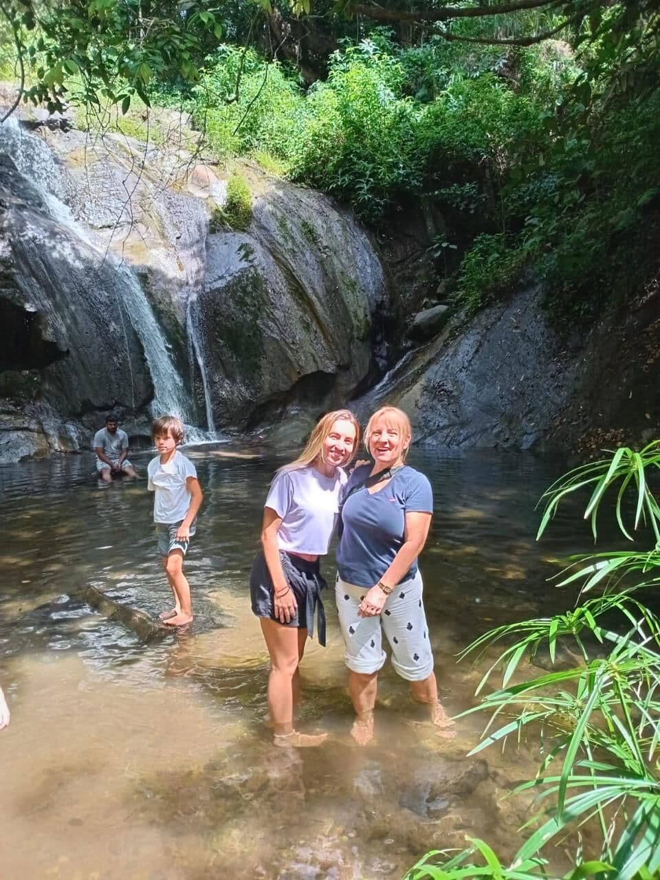 Guests wading in a rock pool below a waterfall